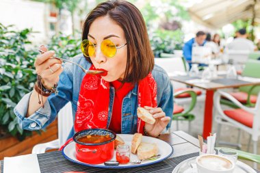 Genç güzel Asyalı kız açık restoranda Macar gulaş çorbası dekoratif kırmızı güveç yemek