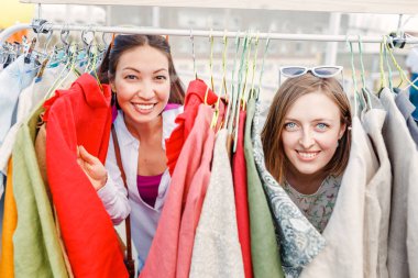Yazlık giysiler açık bit pazarında birlikte alışveriş iki gülen genç kadın arkadaş