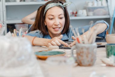 Bir kadın potter yapma ve kil dishware farklı araçları kullanarak bir atölyede kalıp görünümünü yakın çekim