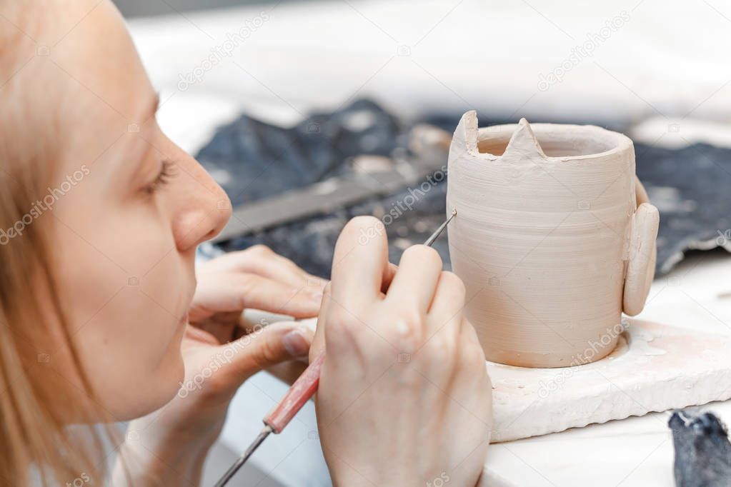 Workshop of clay pottery ceramic, woman decorating dishware pot