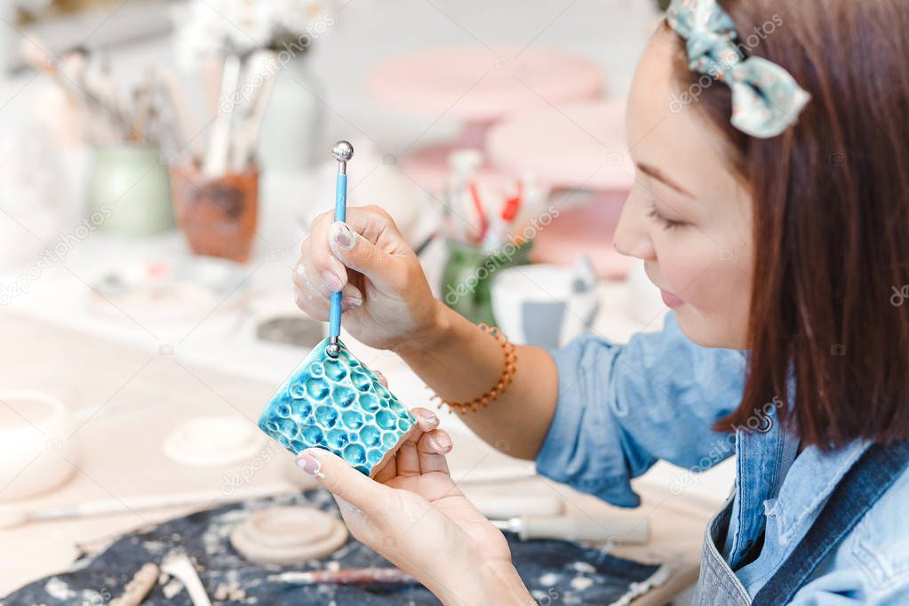 Workshop of clay pottery ceramic, woman decorating dishware pot