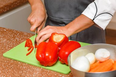 Şef aşçı kesme tatlı biber ve diğer sebze mutfakta masada closeup