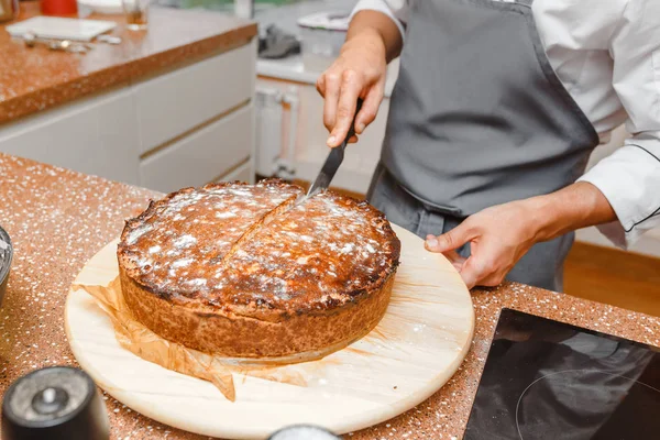 Chef hands making final touches to delicious pie sliced on a rustic kitchen table
