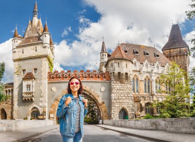 Köprü Vajdahunyad castle Budapeşte, Macaristan önünde poz sırt çantası ile mutlu turist kadın.