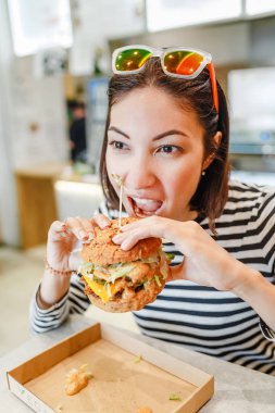 Modern fastfood cafede, öğle yemeği kavramı bir hamburger yiyen kadın