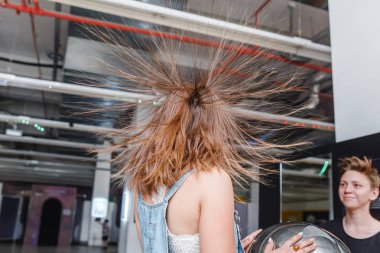01 JULY 2018, UFA, RUSSIA: Portrait of happy woman with standing hair from static electricity at physics museum clipart