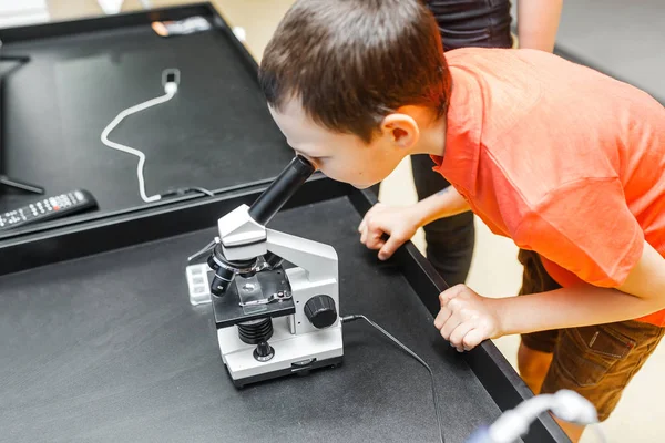 Boy in science class with electronic microscope, education concept