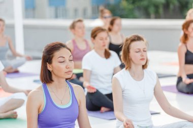 Grup oturma ve yoga asana pozlar, meditasyon ve egzersiz eğitim kavramı germe mutlu sevimli genç kadını