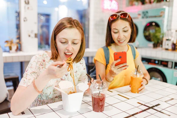 Dvě Ženy Jíst Restauraci Wok Nudle Podívat Smartphone — Stock fotografie