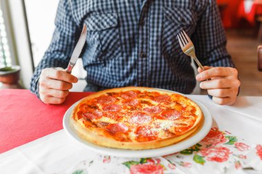İtalyan restoranında çatal ve bıçak kullanarak mutlu aç adam yeme pizza