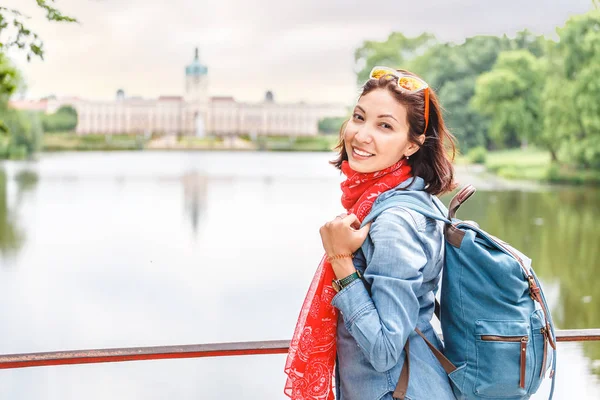 Happy female asian tourist in the baroque garden in front of the ancient architecture of royal Charlottenburg palace. Sightseeing and travel destinations in Berlin and Germany concept