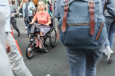 17 Mayıs 2018, Berlin, Almanya: kadın kıdemli bir sakatlık scooter kiralama veya tekerlekli sandalye geçiş yoğun şehir insanların kalabalıklar ile sokak üzerinde
