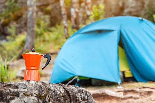 Geyser coffee pot with camping tent in background, kitchenware utensils conept