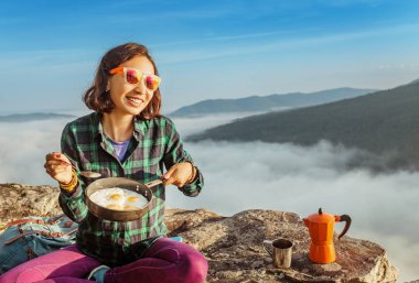Yemek ve kahvaltı pişmiş yumurta ve kahve şafakta Puslu Dağlar yemek kadın seyahat. Kamp malzemeleri ve macera kavramı