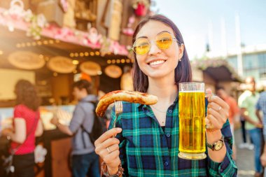 Kızarmış sosis ve içecekler kupa bira adil Pazar Meydanı Almanya, bira ve yemek festivali kavramı'nda yemek genç mutlu asian traveler kadın