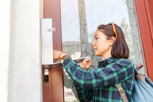 young woman checking her mailbox for new letters near front door