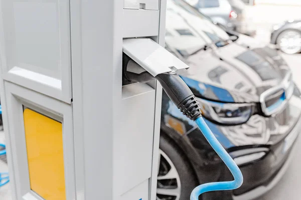 Electric car charging on parking lot at the city street, future transportation and energy concept