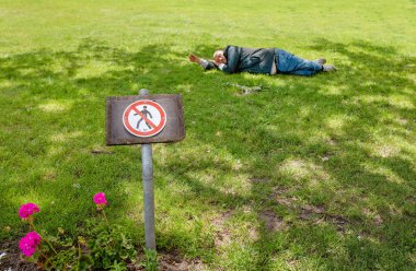 22 Mayıs 2018, Leipzig, Almanya: evsiz adam uyku işareti Park'ın bahçesinde yasaklayan yakınındaki çimenlerin üzerinde