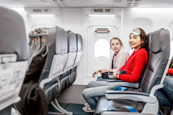 Happy Girlfriends traveling by plane together, air flight passengers