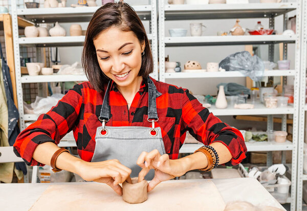 Young woman friends create clay and ceramic art dishes in pottery workshop
