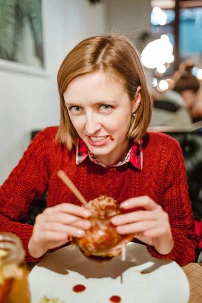 Woman eating burger with ketchup