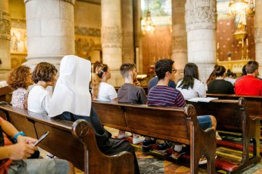 12 Temmuz 2018, Barselona, İspanya: Rahibe kilisede oturur ve diğer insanlarla birlikte dua ediyor