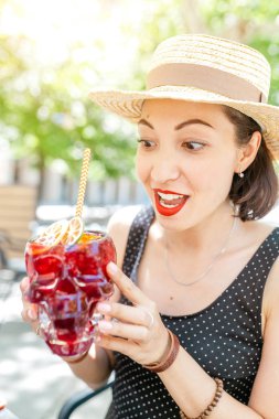 Güzel kız kafede bir kafatası cam kırmızı bir kokteyl içme