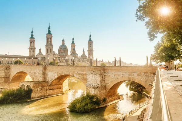 Basilica Cathedral of Our Lady of Pillar and bridge over Ebro River at sunset in Zaragoza, Aragon, Spain. Famous tourist landmark