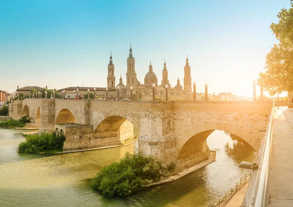 Basilica Cathedral of Our Lady of Pillar and bridge over Ebro River at sunset in Zaragoza, Aragon, Spain. Famous tourist landmark