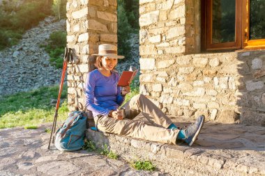 Kitap veya en yakın çelme takmak, dağlarda yürüyüş barınak building yakınındaki planlama harita ile kadın uzun yürüyüşe çıkan kimse