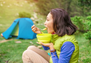 -Ormanda sabah sıcak kahvaltı kadın dağda kamp çadırı yakınındaki sıcak yemek yeme uzun yürüyüşe çıkan kimse