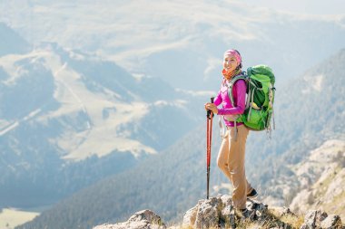 Bir dağ sırtı üstünde duran genç kadın backpacker turist