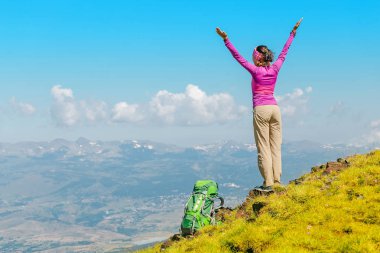 mutlu kadın backpacker ve dağın tepesinde uzanmış kolları olan manzaraya bakarak uzun yürüyüşe çıkan kimse