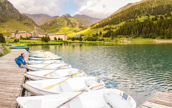 Woman tourist choosing Boat for rent on a mountain lake in the valley of Nuria, Spain. Pyrenees ridge.