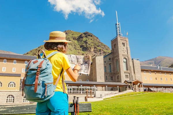 Happy woman traveler with a backpack and a map on the background of the Nuria valley in Pyrenees mountains. Hiking and adventure concept