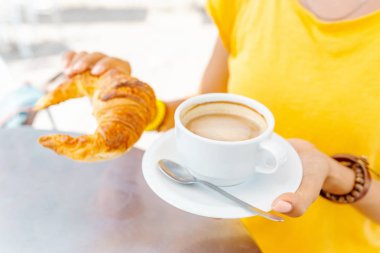 Mutlu kadın kahvaltı croissants ve kahve ile açık kafede sarı
