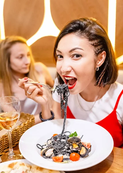 Woman eating delicacy black pasta with cuttlefish ink