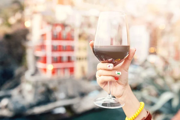 イタリア国旗と女性手ネイルアート チンクエ テッレ リオマッジョーレ町の背景に赤ワインのガラスを保持しています — ストック写真