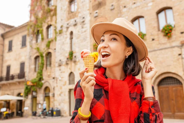 Young hipster traveler eating ice-cream in old Italian town