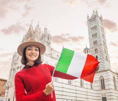 Turist kız İtalya'da yayılıyor. Mutlu genç hipster kadın Siena Duomo Katedrali önünde bayrak ile poz. Tatil ve gezi Tur Avrupa'da