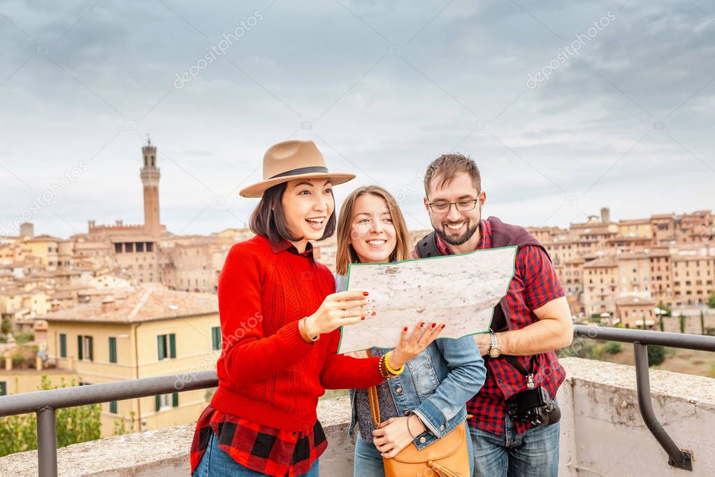 Multiracial group of friends tourists looking at map in an old city in Italy. Travel and adventure concept