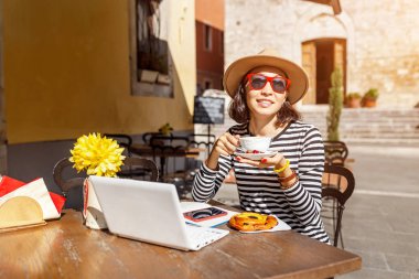 Portre resim kullanarak ve akıllı telefon, defter ve laptop açık Cafe ile çalışan bir kadın
