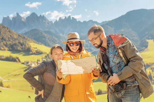 Active three friends travel and reading map during autumn holiday and vacation in the mountains of the Dolomites in the Bolzano region in Italy
