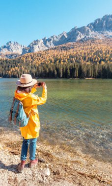 Gezgin kadın inanılmaz bir Misurina dağlar göl fotoğraflarını çekmek için cep telefonu kullanın