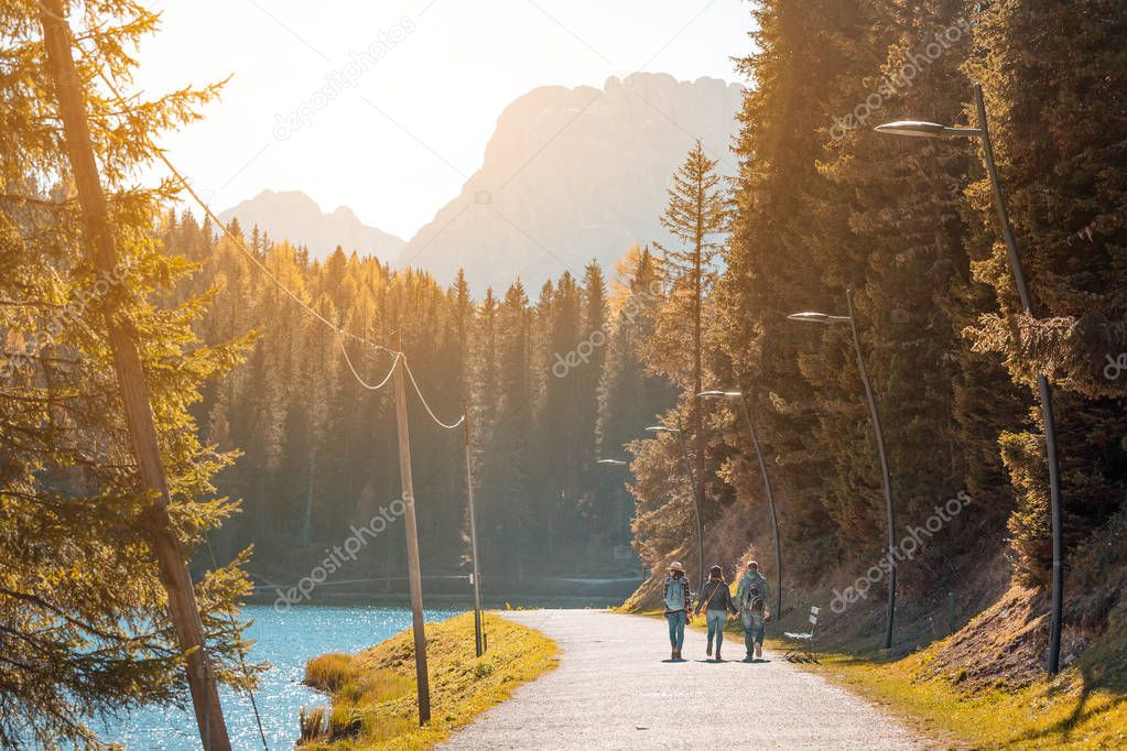 Happy three friends travel in Italian Dolomites mountains stading on the coast of a Misurina Lake