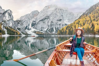 Ahşap klasik tekne yüzen ve İtalyan Alpleri dağlarda Braies gölde yelken oturan mutlu Asyalı kadın seyahat ve tatil kavramı hayal