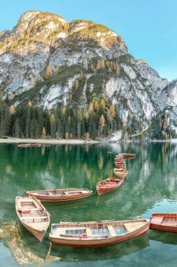 A magical panoramic landscape with calm colors of the famous lake Braies in the Dolomites Alps during autumn season. A popular tourist attraction clipart