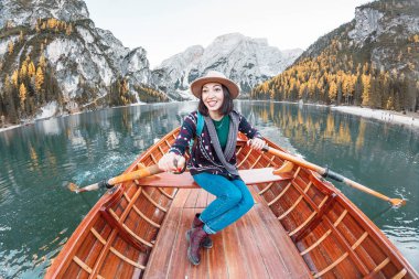 Ahşap klasik tekne yüzen ve İtalyan Alpleri dağlarda Braies gölde yelken oturan mutlu Asyalı kadın seyahat ve tatil kavramı hayal