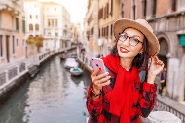 Genç mutlu asian traveler kadın ile smartphone bir dar kanal ve Venedik sokak iskelede. İtalya kavramı tatil