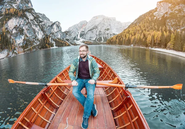 man in boat floating and rowing on Pragser Wildsee Lake, or Lago Di Braies in Italian Dolomites Alps